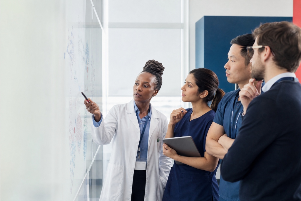 Doctors and scientists analyzing whiteboard research diagram